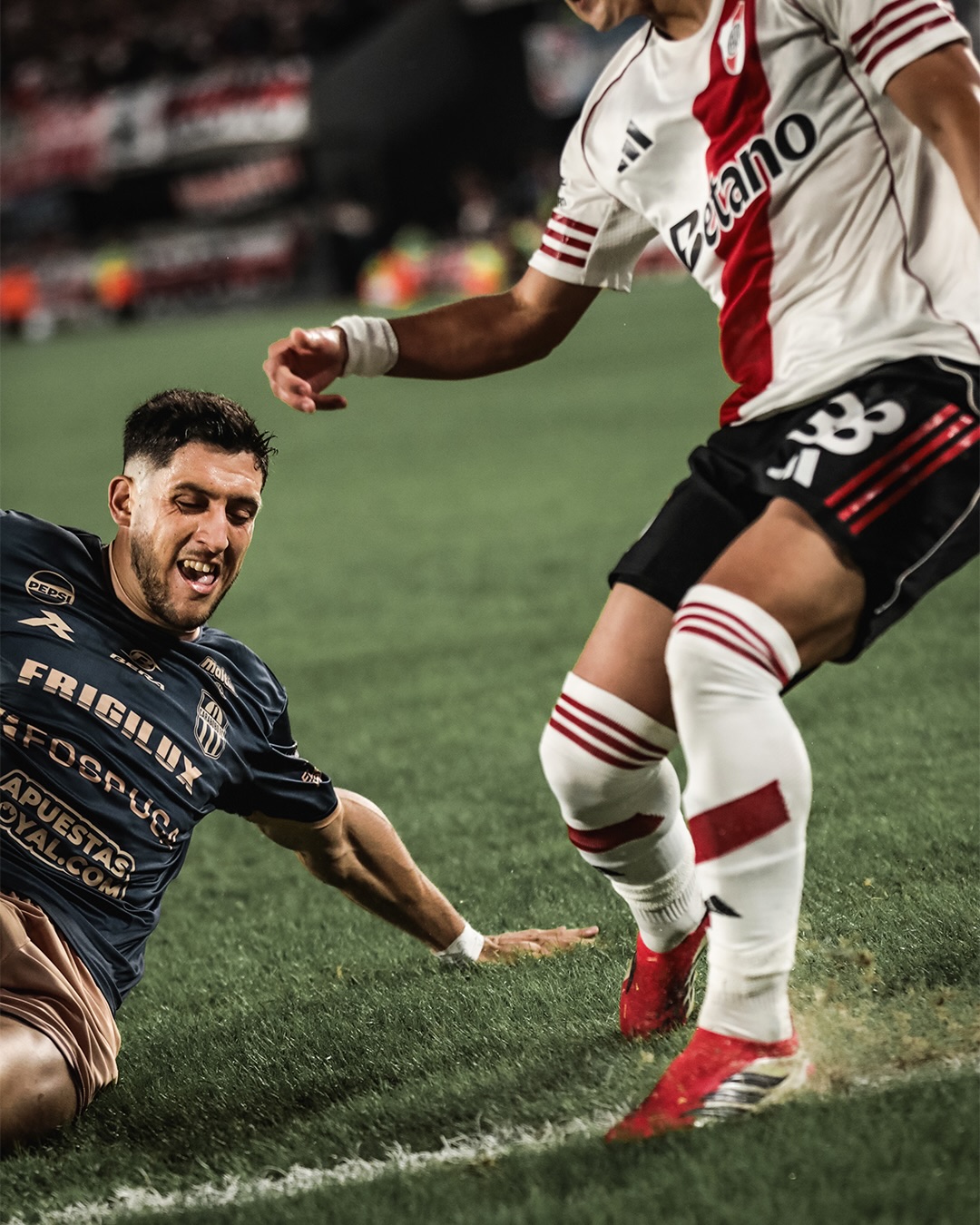 Ezequiel Neira se desliza en una entrada defensiva frente a un jugador de River Plate.